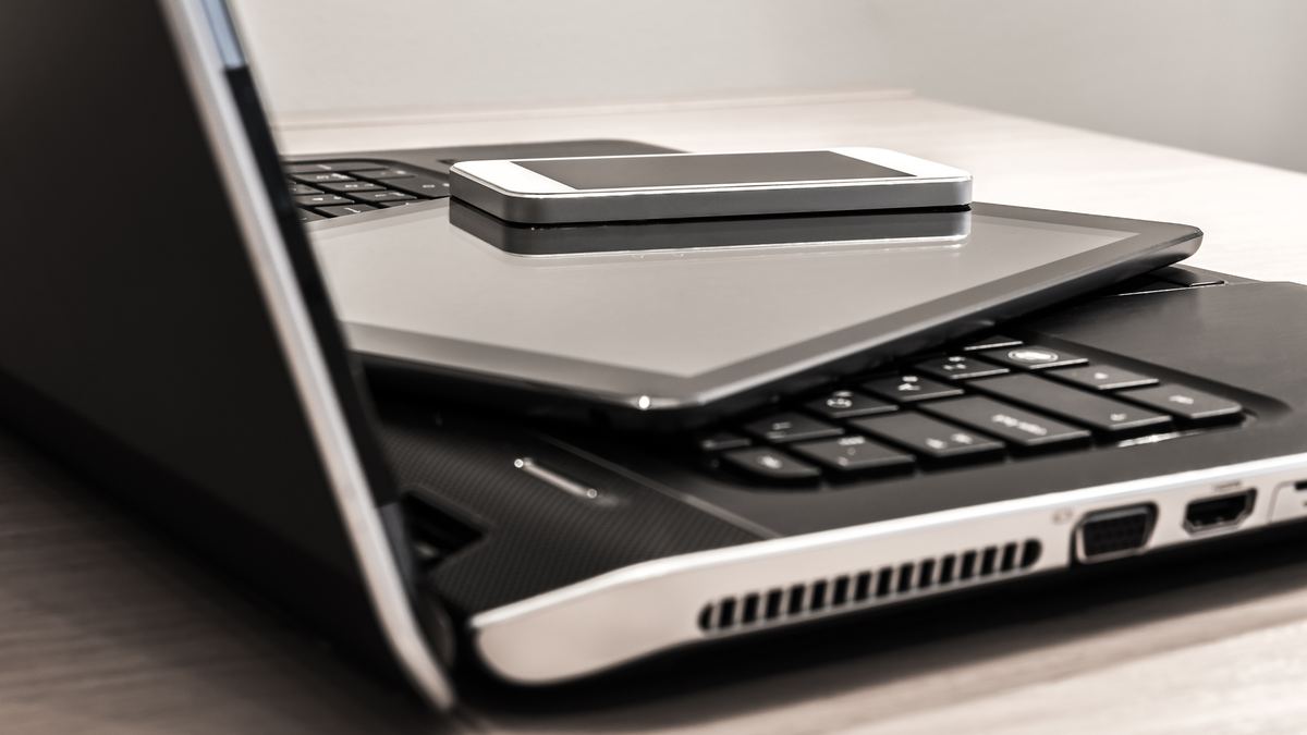 A smartphone resting on a tablet and laptop, ready for reuse assessment